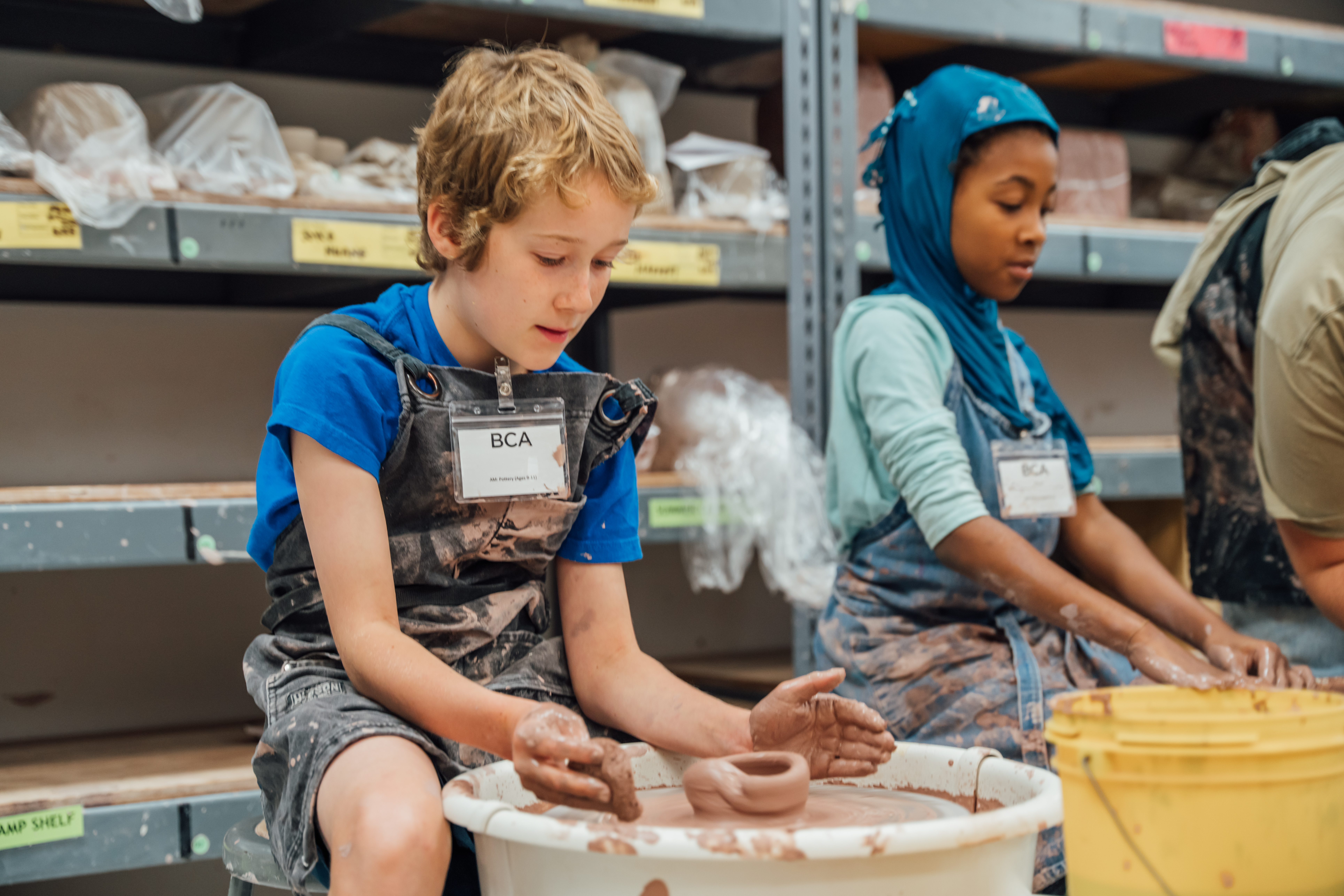 Two campers create pottery at the BCA Studios pottery wheel.