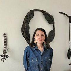A woman stands in front of her sculptures.