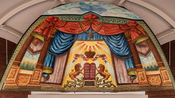 a painted mural of a stage with red and blue curtains, two lions, and the middle has a crown.