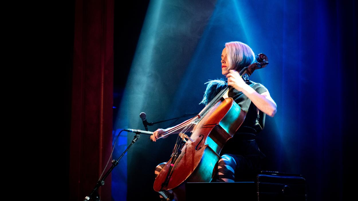 An image of a woman playing cello under blue lights.