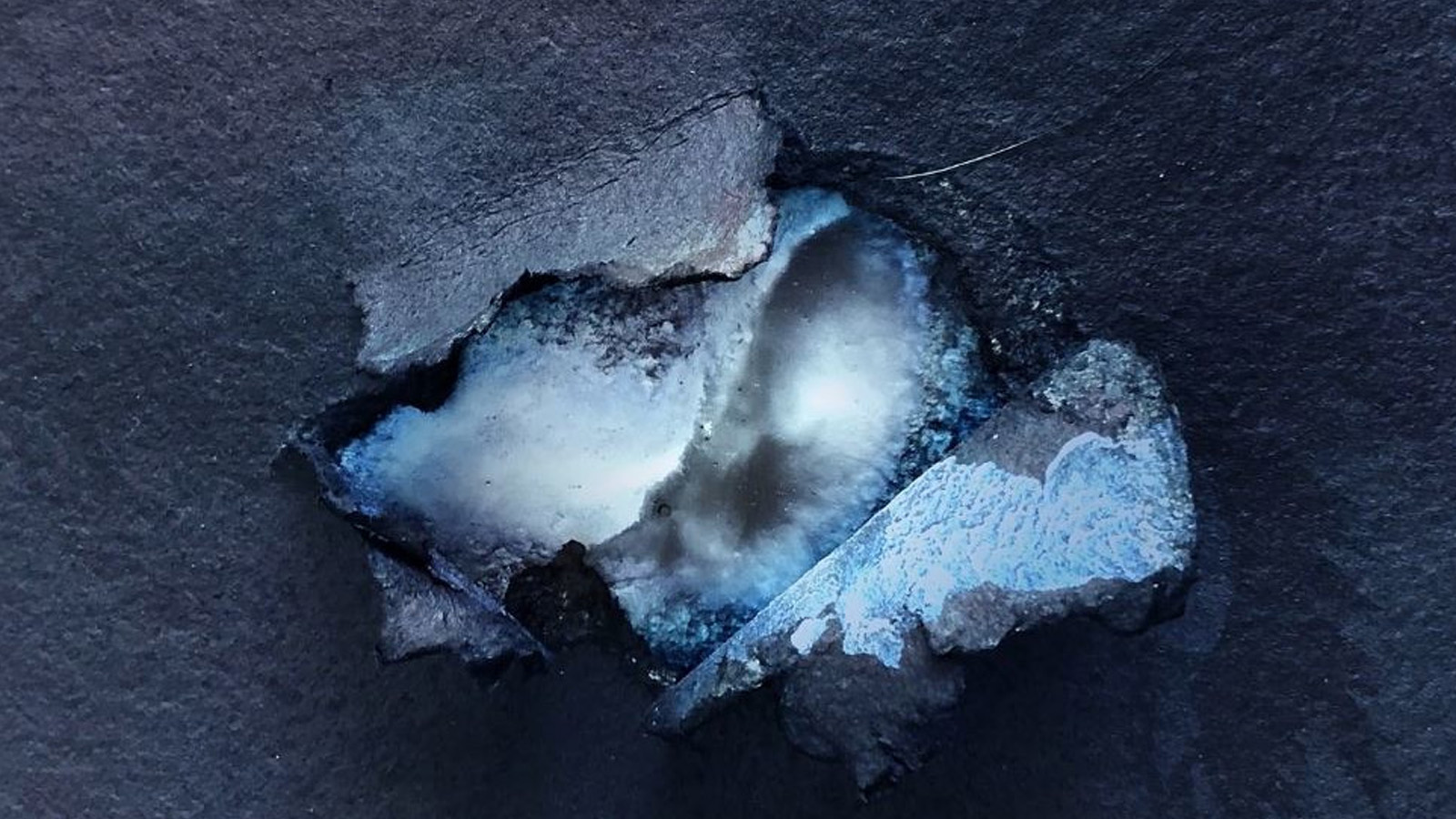 Blue abstract art, with a hole starting to tear into the center