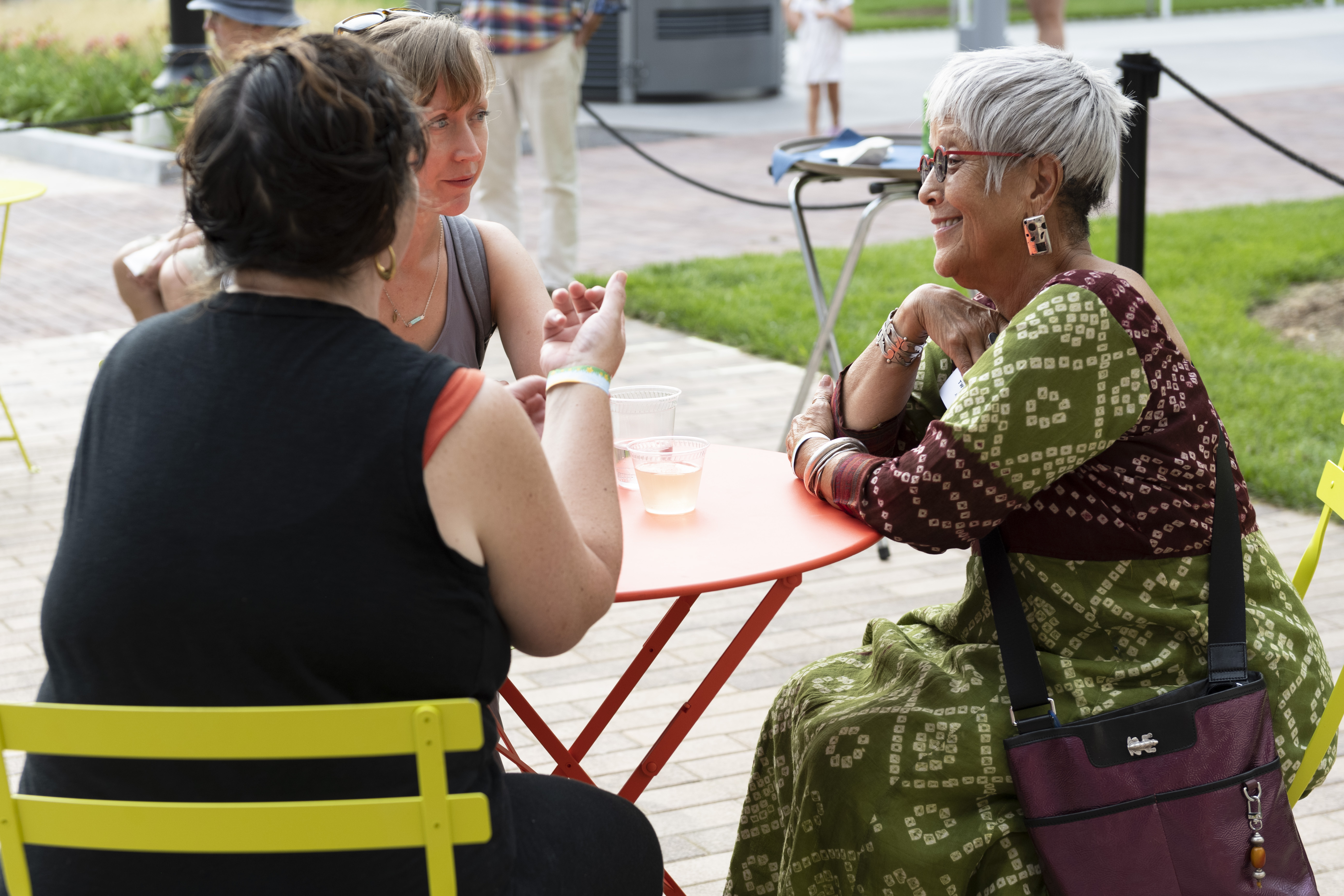 Three people chatting at an outdoor table.