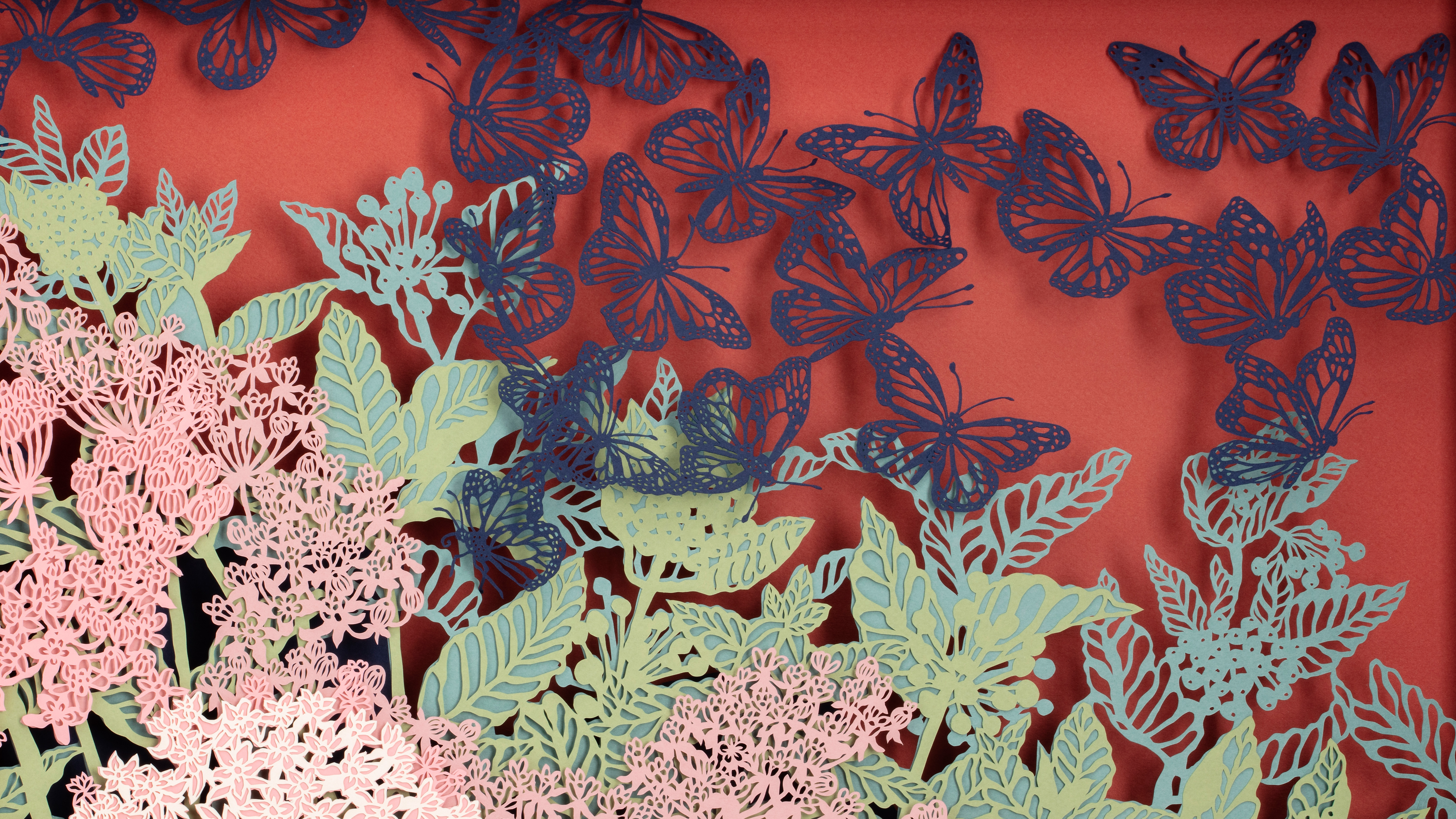 Navy blue cut paper butterflies swarm across a red background with foamy pink cut paper flowers with green leaves