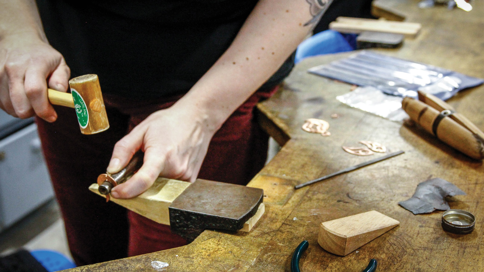 using jewelry tools to stamp out a set of copper earrings