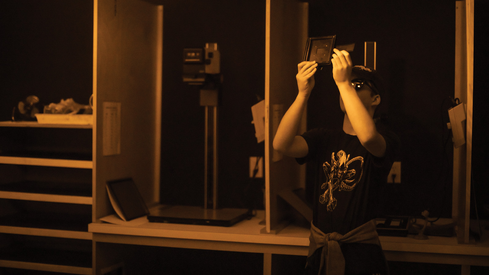 a teen looking at negatives in a darkroom