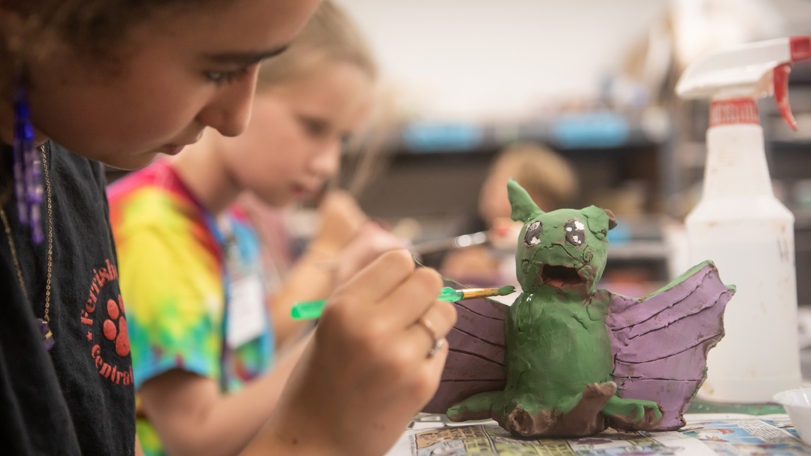 A youth painting a ceramic dragon in a clay studio 