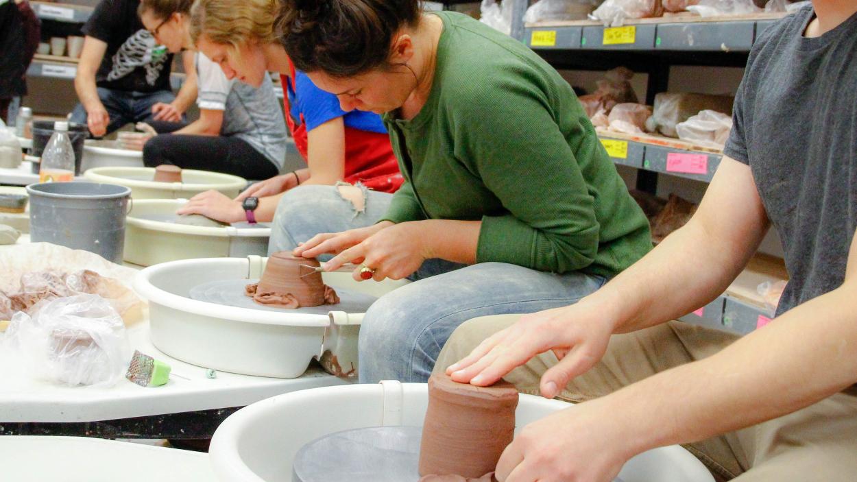 A group of adults at the pottery wheel