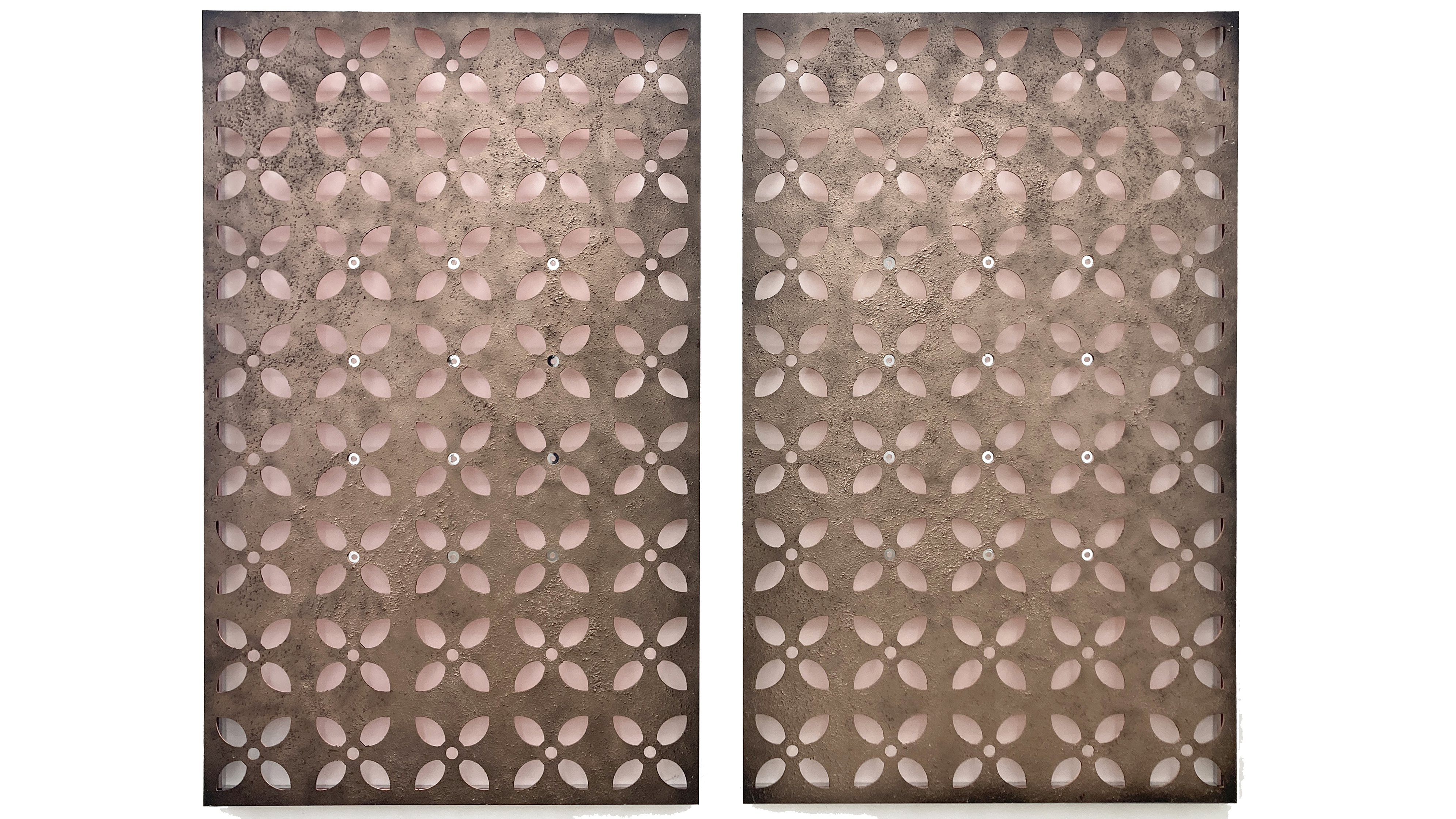 A photograph of a sculpture that consists of two rectangular flat metal panels with rows of geometric floral shapes stamped out.