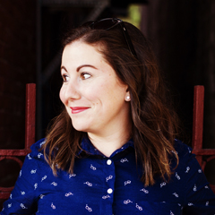 An image of a woman in a blue shirt, smiling and looking off to the side.