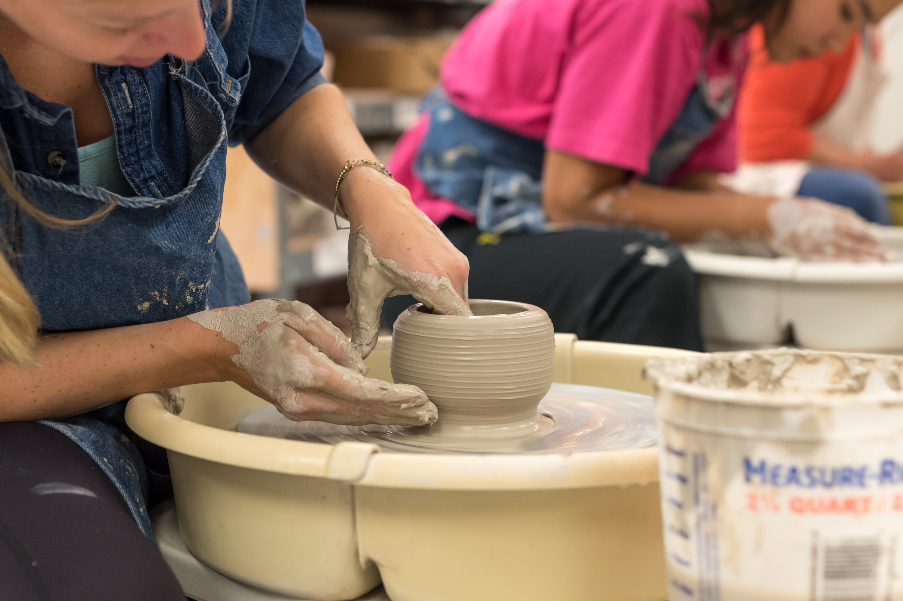 A woman works on a clay pot on a wheel in the BCA clay studio.