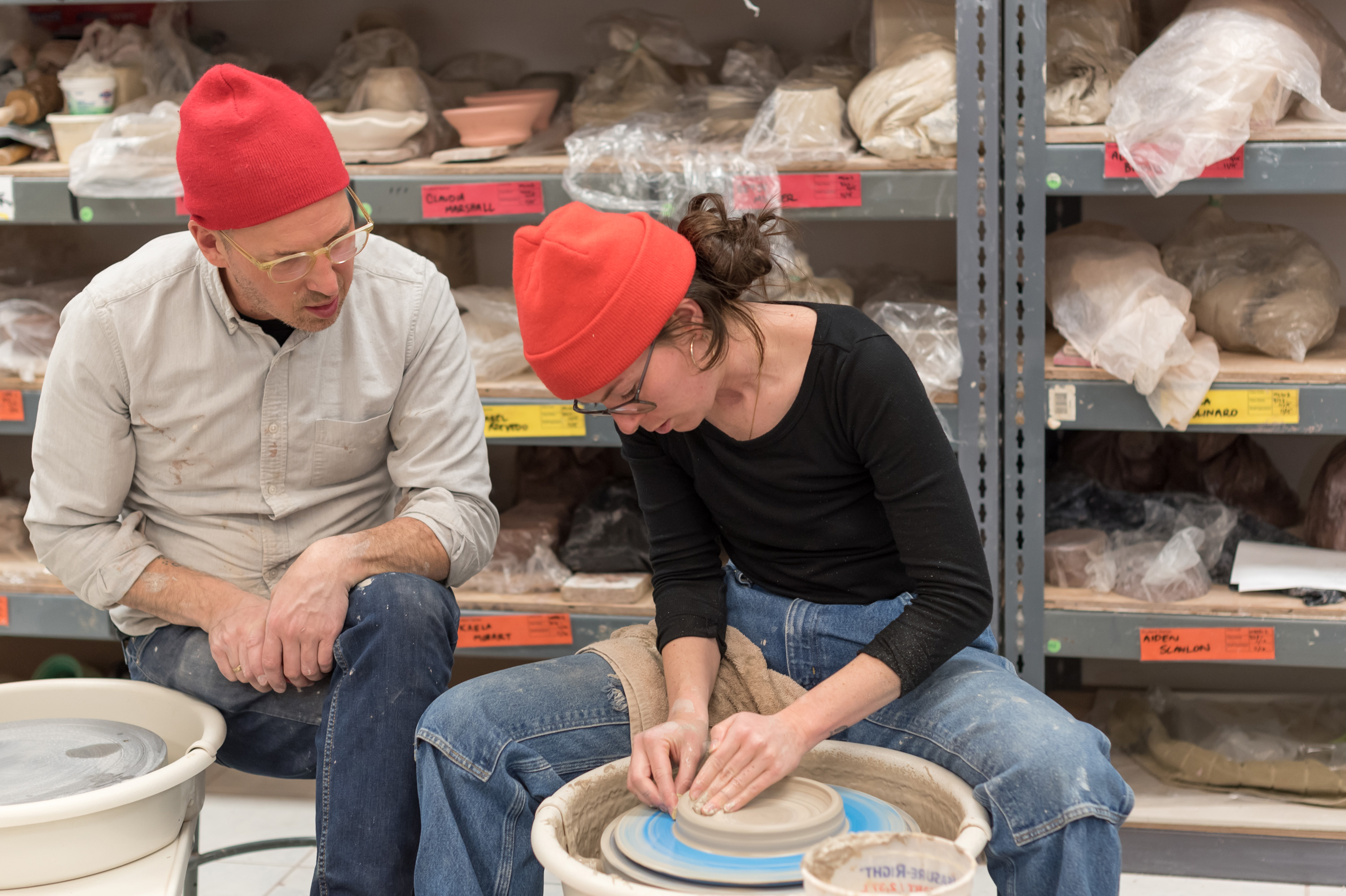 Art instructor watches his student as she molds clay in the studio.