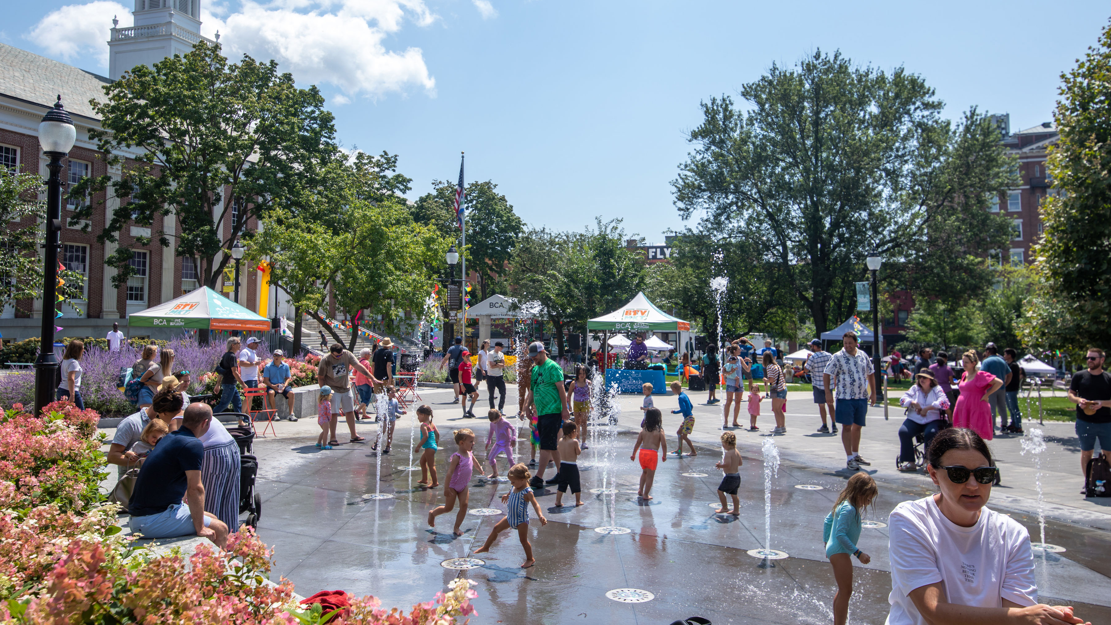 a hpotto of burlington city hall park splash fountain filled with dancing children