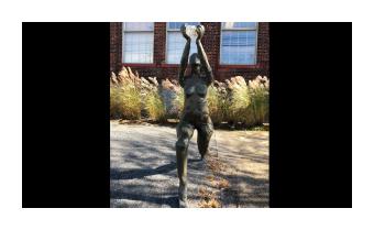 Bronze sculpture of a woman reaching up with both hands