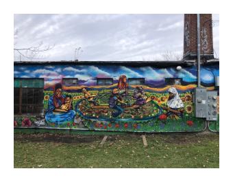 Side view of mural on 339 Pine St of children playing on a merry-go-round and mother holding her child.
