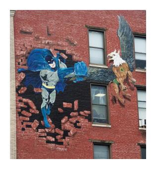 a trompe l'oeil mural of batman bursting through the side of a red brick building, chasing an eagle