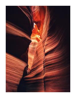 An abstracted photograph of a rocky crevasse of orange, striated rocks