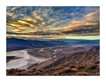 A photograph of a salt flat with mountains and clouds overhead