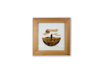 circular image of a person a field with the sky of them made out of wood within a wood shadow box