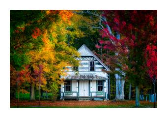 photograph of white country house with foliage in yellows and reds