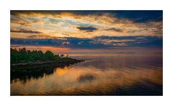 photograph of water reflection at dusk with lighthouse in orange and indigo