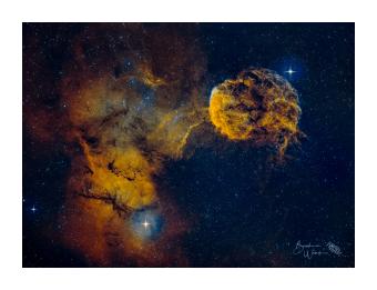Photograph of a jellyfish nebula in bright yellows and deep blues. 