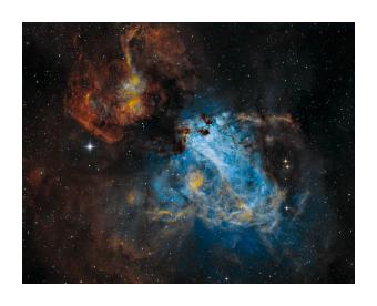 Swan nebula in swirling blues, oranges, and yellows against the black of space. 