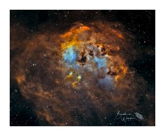 Photograph of a nebula in orange, blues, and greens. 