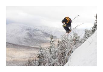 Photograph of a skier midair going down a mountain. 