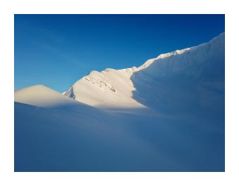 Photography of a snow-covered cliff peak.