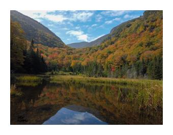 Photograph of a mountain valley reflecting back into the lake, blues and oranges.