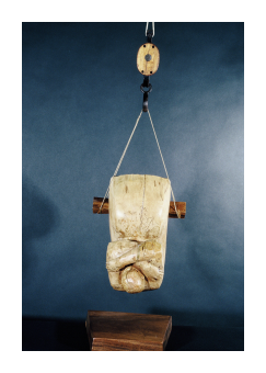 Birch and walnut sculpture suspended from a hook where the figure is facing up. 