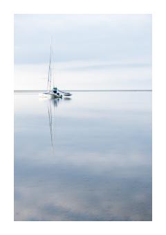 Photograph of a boat on the water in pale blue.