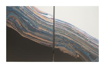 Acrylic painting depicting two sides, black & white, with a river in between in gold, blue, and reds that melts into the two sides. 