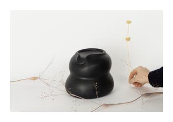 Sculpture depicting two wide rounds on top of each other, the top having a spout. 