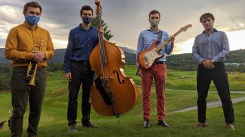 Andrew Richards Ensembe. 4 Musicians holding instruments standing in a grassy field with the Vermont Mountains behind them.