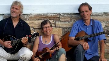 Atlantic Crossing: 3 band members holding traditional folk instruments infront of a stone wall