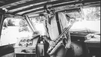 black and white photo of artist holding a saxophone in an abandoned boat