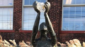 Bronze sculpture of a woman reaching up with both hands