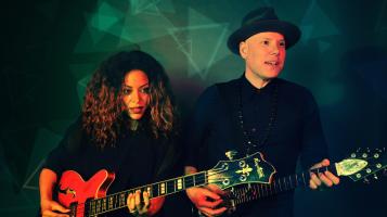 Dwight and Nicole both hold electric guitars.