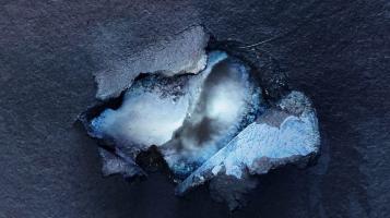 Blue abstract art, with a hole starting to tear into the center