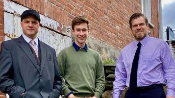 The three men that make up the Vermont Jazz trio stand in front of a brick wall.