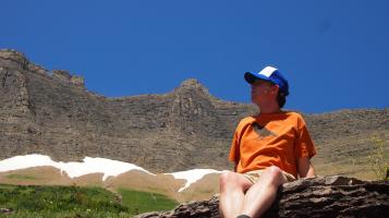John Townsend sits on a rock with mountains in the background.