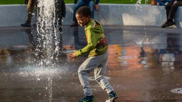 young kid playing in a splash fountain
