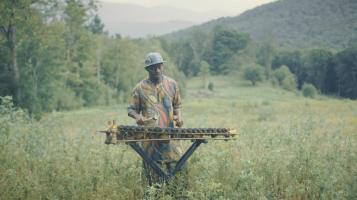 Ousmane Camara, the leader of Sabouyouma plays a balafon in a field.
