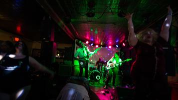 The Wet Ones perform on a stage lit by green and pink lights.