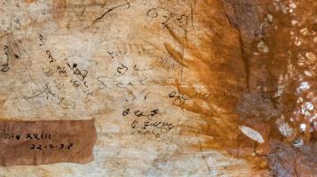 distressed abstract art, black native writings on brown worn substrate