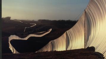 A photograph of Christo and Jean Claude's installation piece, a fence of white fabric snaking across the hills of northern California