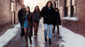 The band walking down a snowy alley in late afternoon sunlight