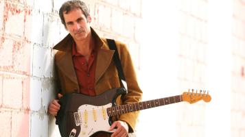 Dave standing in front of brick wall holding a Fender Stat