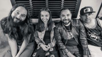 black and white photo of band sitting on a couch looking real happy
